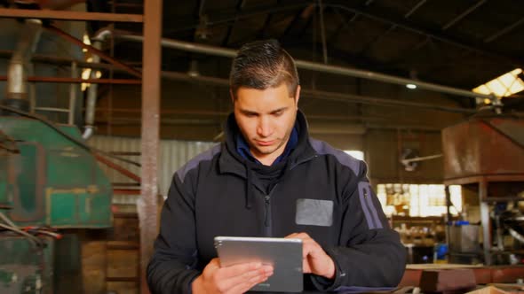 Worker using digital tablet in foundry workshop 4k