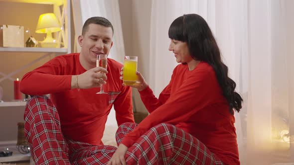 Happy Man Clinking Champagne Glass with Woman Drinking Orange