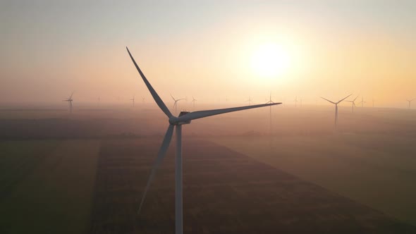 Windmills with rotating wings at sunrise or sunset or sunrise.