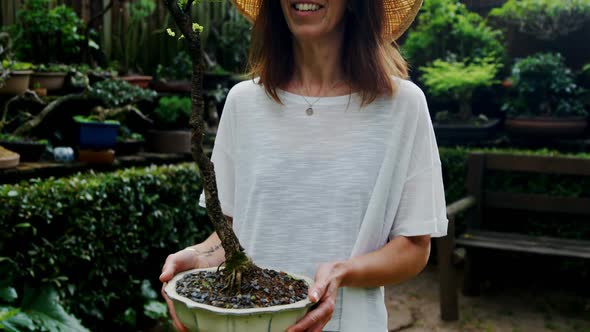 Mature woman holding a plant in the garden 