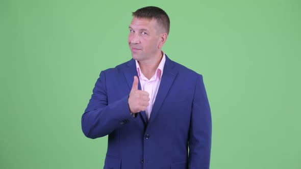 Happy Mature Macho Businessman in Suit Giving Thumbs Up