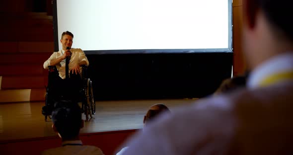 Young Caucasian disabled businessman speaking in business seminar in auditorium 4k