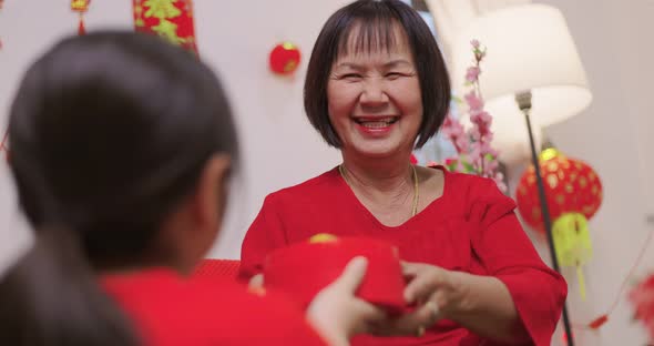 Happy Asian Girl Giving Her Grandmother Orange for Chinese New Year Blessing Gift.