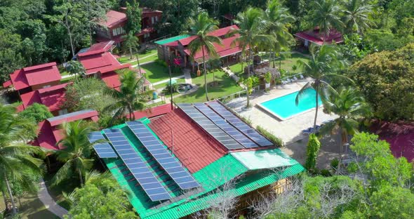 View of red roofs, green tropical landscape, pool and solar panels on rooftop of hotel ecologico Lom