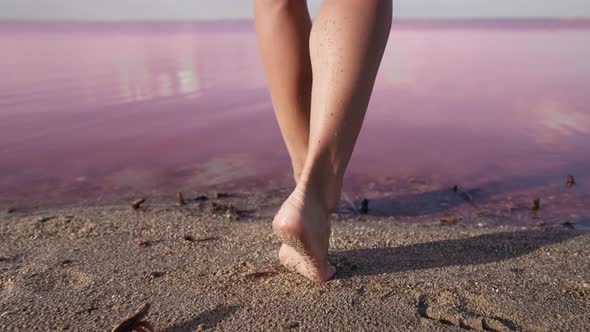 Bare Female Feet Go Wet Sandy Shore to Pink Lake