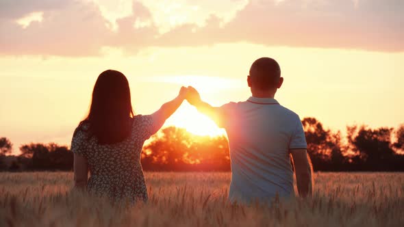 A Happy Family Holds Hands and Looks at the Sunset