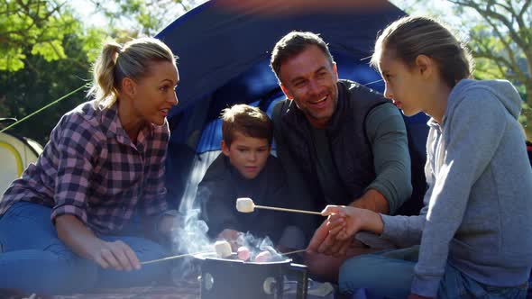 Family roasting marshmallows outside the tent