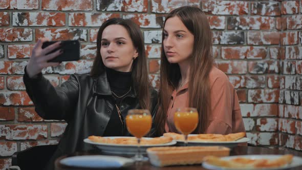 Two Girls are Sitting in a Cafe and Taking a Selfie on the Phone