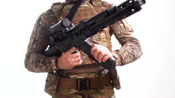 Man in combat camouflage and body armor attaches a magazine of ammunition