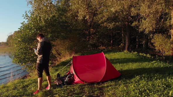 Camper using smartphone near tent