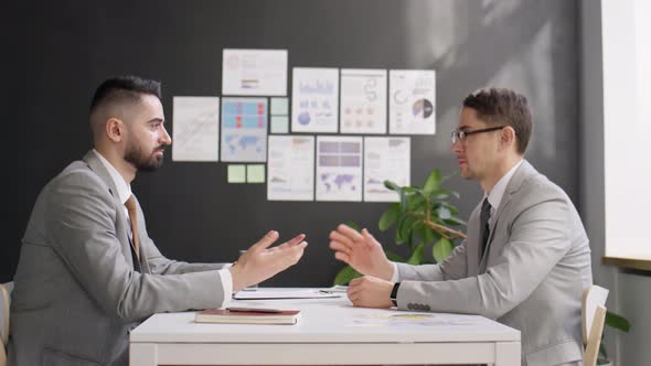 Two Businessmen Talking and Shaking Hands at Office Meeting