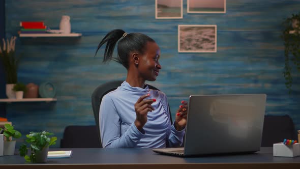 Smiling African American Freelancer Listening Music at Laptop