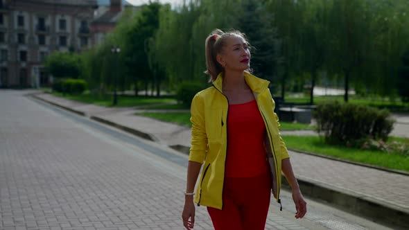 Adult Woman is Wearing Bright Red and Yellow Clothes is Walking in Morning in City