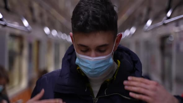 Young Man Putting on Protective Mask in Metro