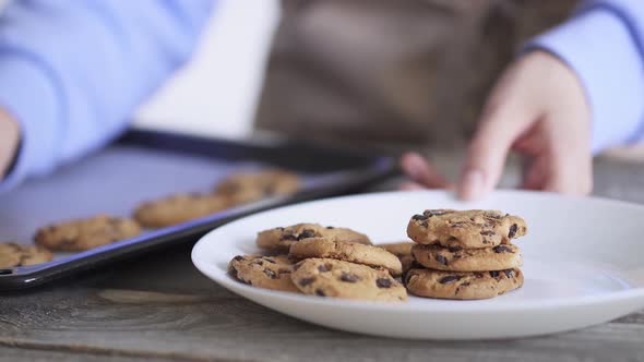 A Woman's Hand Takes A Cookie. Baking Cookies With A Chocolate Drop Are On A Baking Sheet.