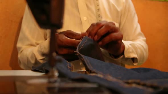 Local sewer tearing textile at market workshop in Goa.