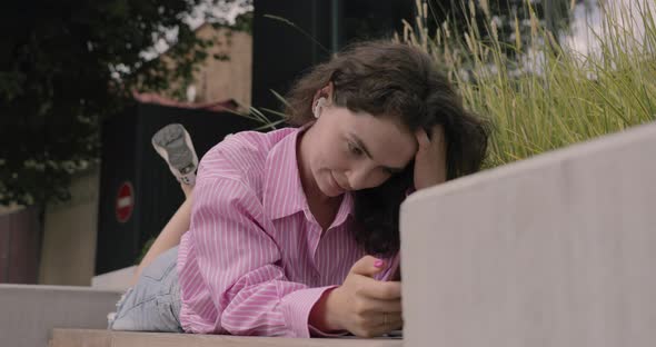 Young white woman listen to streaming music with wireless headphones on mobile phone