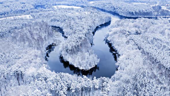 Winter winding river and snowy forest. Aerial view of Poland