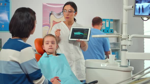 Stomatologist Pointing on Digital Screen Explaining Xray to Mother