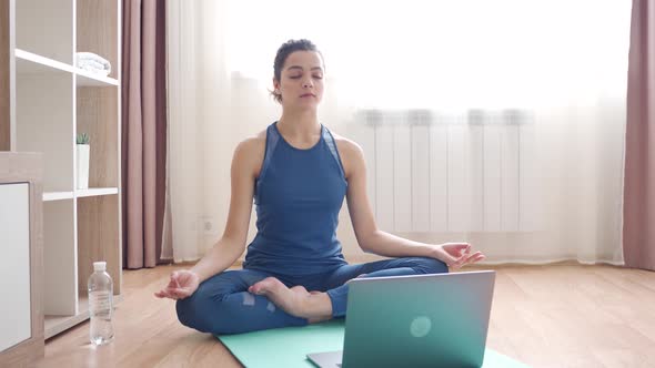 Happy Young Sporty Slim Fit Woman Doing Hatha Yoga and Watching Video on Laptop