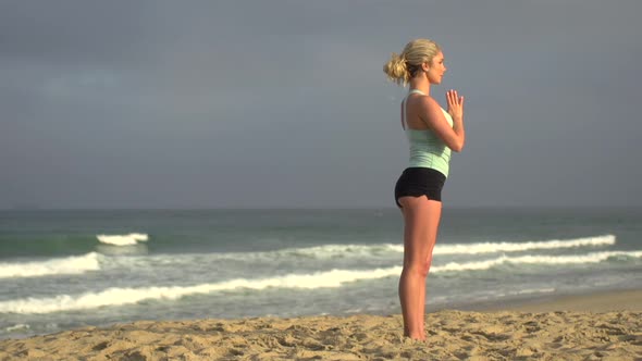 A young attractive woman doing yoga on the beach.