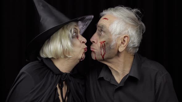 Elderly Man and Woman in Halloween Costumes Making a Kiss. Witch and Zombie