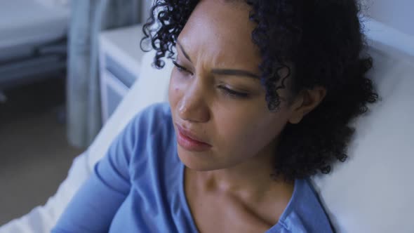 Portrait of african american female patient lying on hospital bed feeling pain