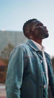 Black Man Looking at Skyscrapers in City