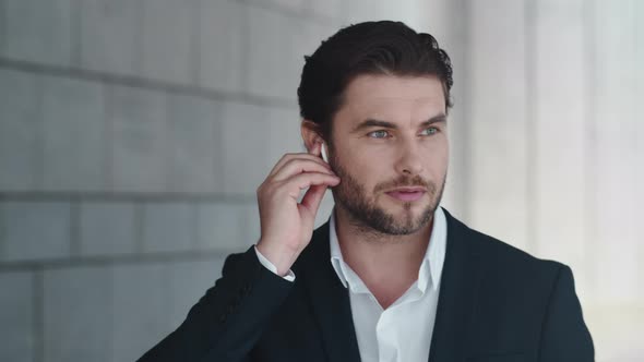 Businessman Talking By Wireless Earphones in City. Employee Using Earbuds