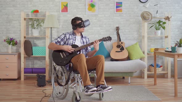 Young Man Disabled in a Wheelchair in Virtual Reality Glasses Musician Plays the Electric Guitar