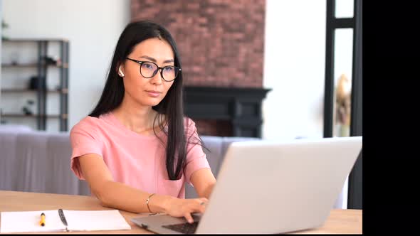 An Attractive Young Asian Woman is Using a Laptop Indoor