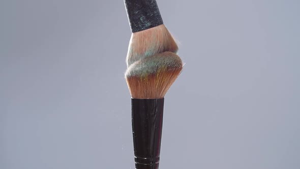 Make-up Brush with Green Powder Splashes Explosion on Gray Background on Slow Motion