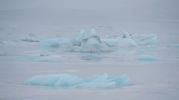 Static, shot of turquoise icebergs, on the sea, at skaftafellsjokull glacier,  on a cloudy day, at t