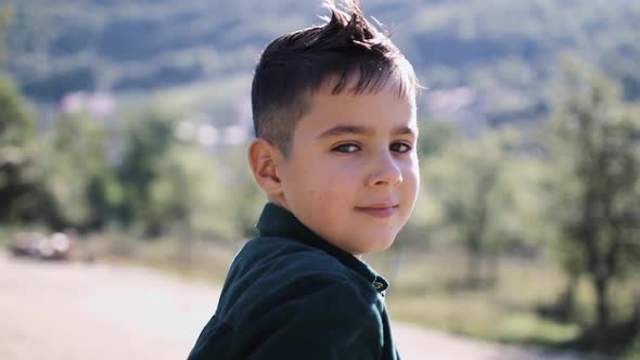 8Yearold Boy Looks Into the Camera Against the Backdrop of Beautiful Mountains