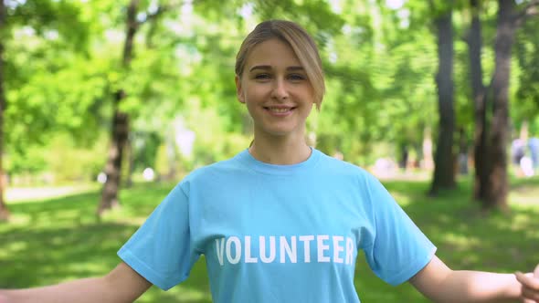 Young Pretty Woman Pointing at Volunteer Word on Blue T-Shirt