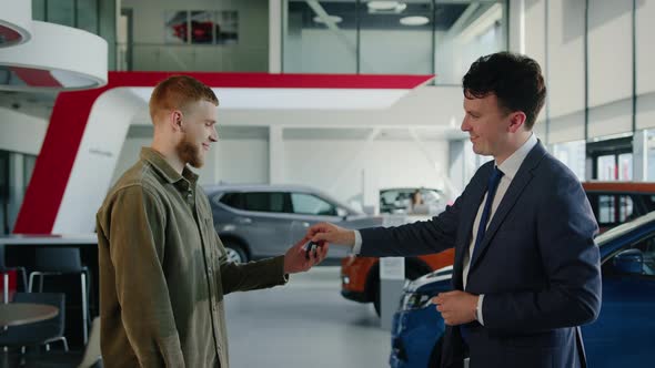 The Manager in a Suit and Tie Hands the Keys to the Car Buyer