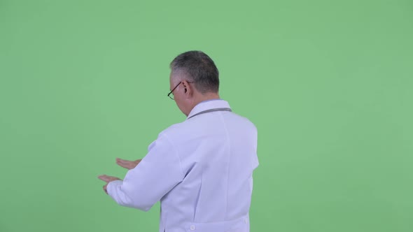 Rear View of Mature Japanese Man Doctor Touching Something