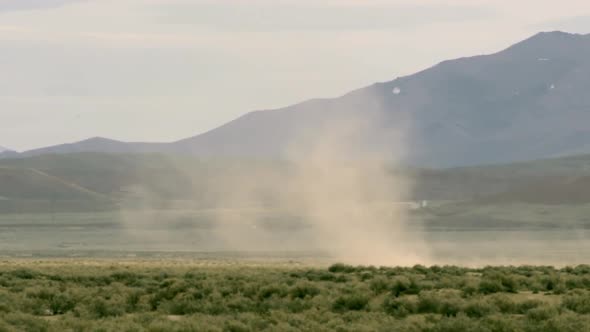 Dust Devil blowing across planes in Nevada in front of a mountain