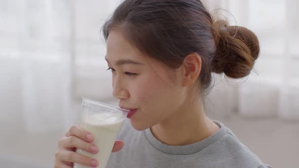 Healthy Young Asian woman Drinking milk with calcium for strong bone at home