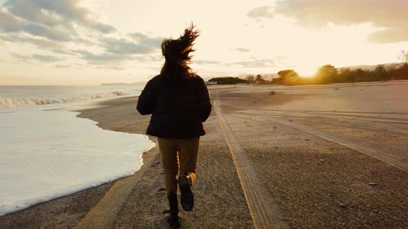 Girl run on the beach at sunset 