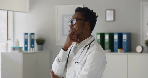 Thoughtful Afroamerican Confident Doctor Standing in Office Looking Away