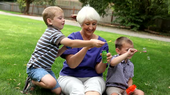 Senior woman and two young boys blowing bubbles