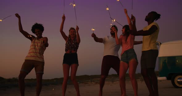 Young adult friends having fun on the beach at night with sparklers 4k