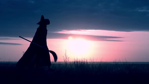 a Witch with Besom at Halloween on the Hill Evening Skyline