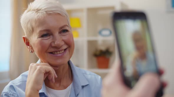 Close Up of Male Hand Holding Smartphone and Taking Picture of Beautiful Aged Wife