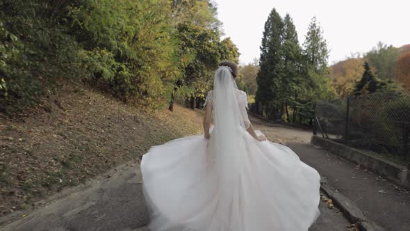 Beautiful and Lovely Bride in Wedding Dress Running in the Park. Slow Motion