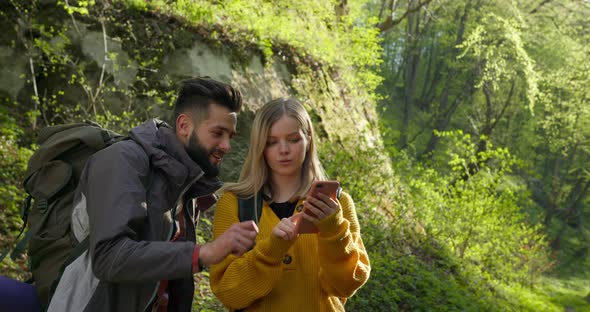 A Guy and a Girl Are Looking at a Map on Their Smartphone