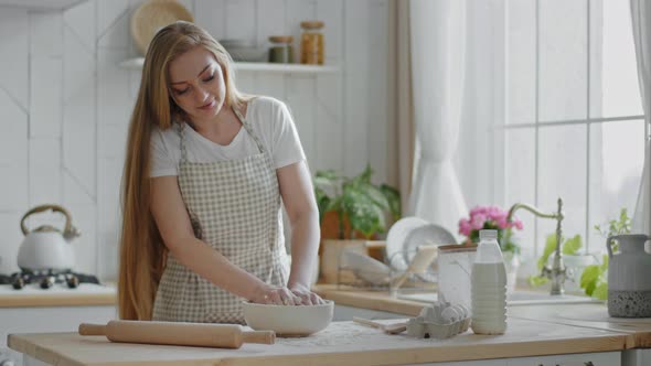 Caucasian Woman with Long Hair Adult Housewife Female Baker Cook Wears Apron Stands in Modern Home