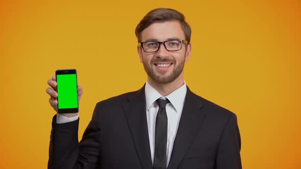 Man in Suit Holding Smartphone With Green Screen, Showing Thumbs Up Business App