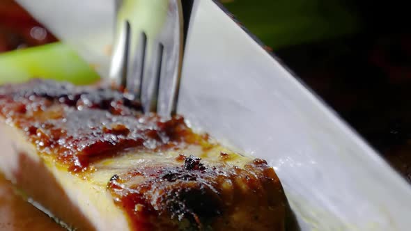 Slices of roasted meat. Beef roasted meat on grill. Fork and knife cutting the slices of roasted whi